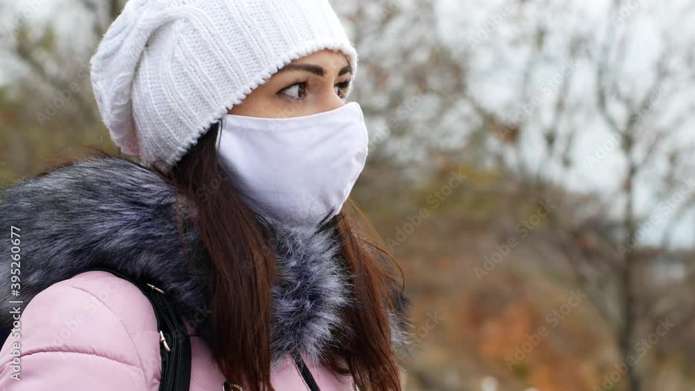A woman with long dark hair in a mask from air pollution and the Covid19 coronavirus walks in the park. Close-up of a woman in a mask protecting against coronavirus outdoors. Stay at home. A woman with long dark hair in a mask from air pollution and the Covid19 coronavirus walks in the park. Close-up of a woman in a mask protecting against coronavirus outdoors. Stay at home.