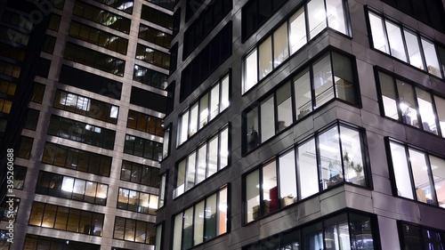 Pattern of office buildings windows illuminated at night. Lighting with Glass architecture facade design with reflection in urban city.