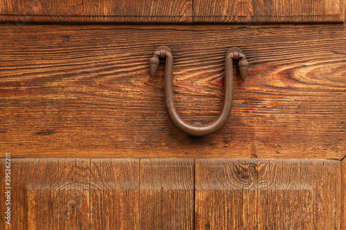 Close-up of an antique iron knob on an antique wooden door