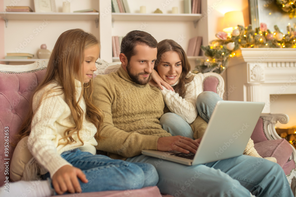 Young family sitting looking excited while having a video call Young family sitting looking excited while having a video call