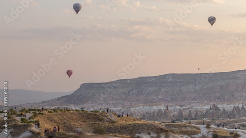 People watching a beautiful sunrise with colorful hot air balloons flying in clear morning sky aerial timelapse in Cappadocia  Turkey