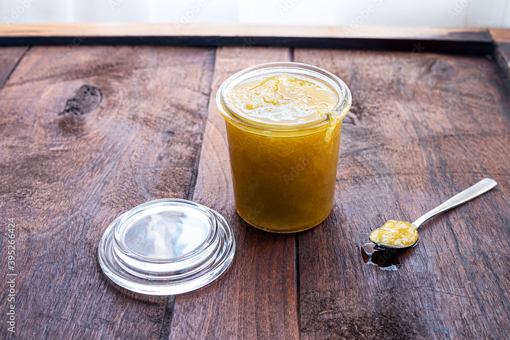 An opened glass jar of homemade jam and a spoon with jam on a dark old wooden background, concept of healthy organic breakfast An opened glass jar of homemade jam and a spoon with jam on a dark old wooden background, concept of healthy organic breakfast
