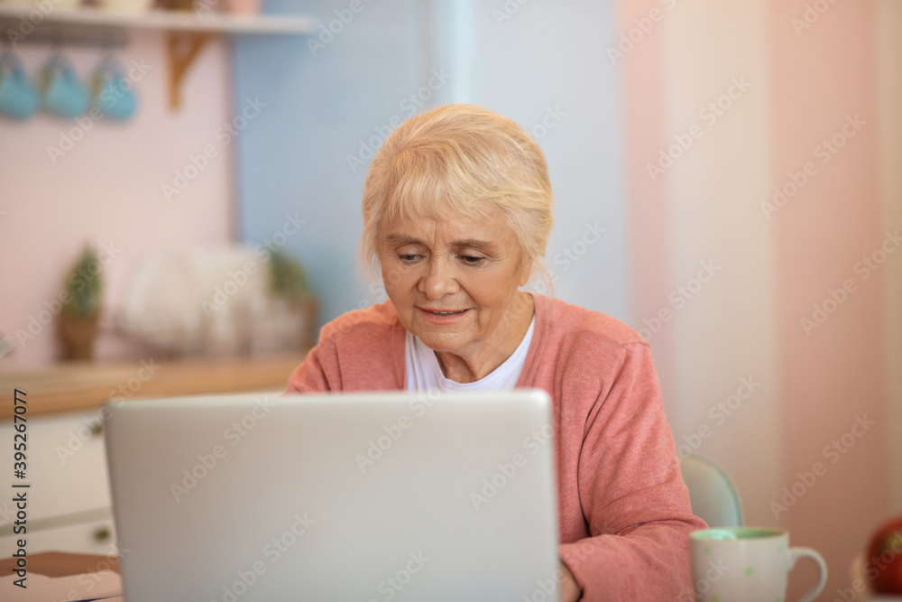 Elderly woman sitting at the table and looking involved Elderly woman sitting at the table and looking involved