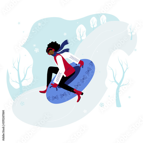 A beautiful and happy girl with blue scarf and gloves sledding down the hill sitting on the snow tube.