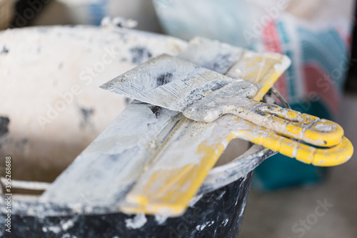 Bucket with putty and putty knife is on the floor room of apartment is under construction, remodeling, renovation, extension, restoration and reconstruction photo