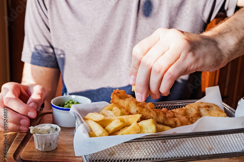 Man's hand sprinkling with lemon fish and chips