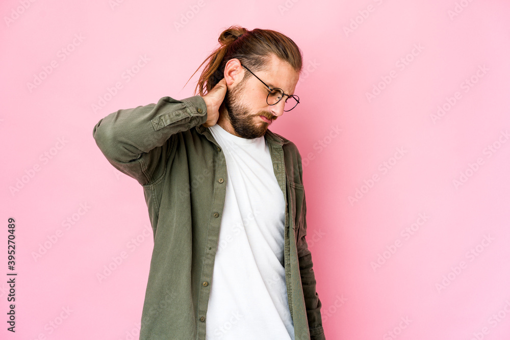 Young man with long hair look having a neck pain due to stress, massaging and touching it with hand. Young man with long hair look having a neck pain due to stress, massaging and touching it with hand.