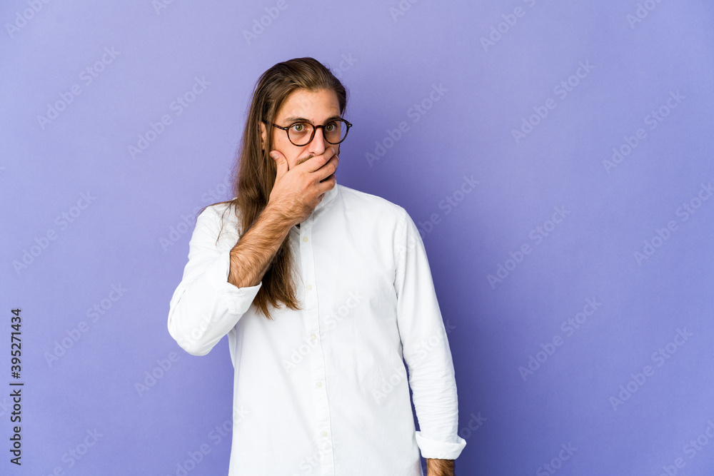 Young man with long hair look thoughtful looking to a copy space covering mouth with hand. Young man with long hair look thoughtful looking to a copy space covering mouth with hand.