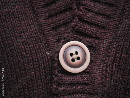 Macro snapshot of knitted texture. Warm sweater. Fashion and texture concept with button