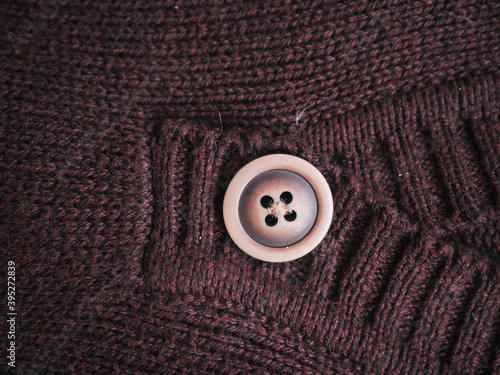Macro snapshot of knitted texture. Warm sweater. Fashion and texture concept with button in the middle