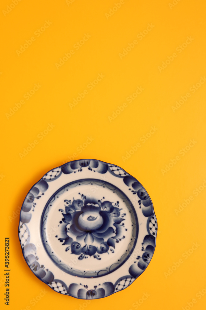 Top view of a blue plate on a yellow background. Gzhel Top view of a blue plate on a yellow background. Gzhel