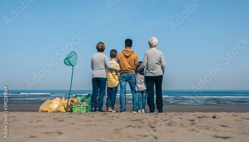 Group of volunteers backwards watching the sea after cleaning the beach