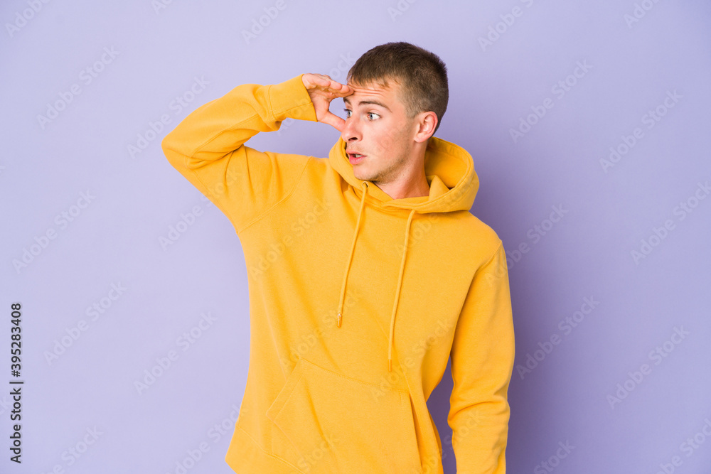 Young caucasian handsome man looking far away keeping hand on forehead. Young caucasian handsome man looking far away keeping hand on forehead.