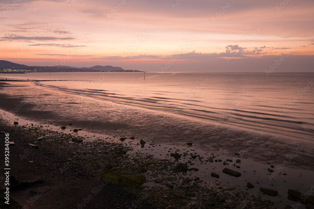 Summer evening at Colwyn bay, North Wales. Warm summer sunset and a rocky beach