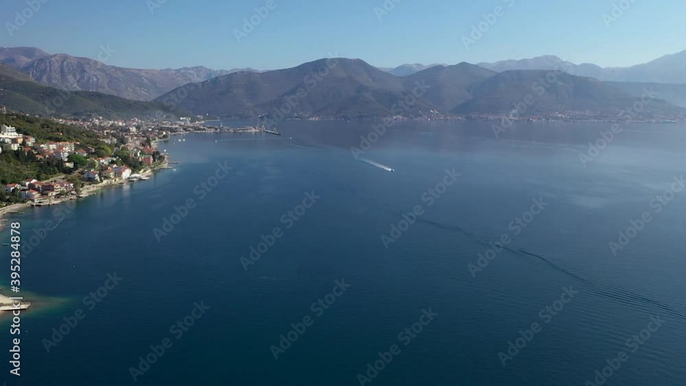 Boat sailing near coast town. Adriatic sea and Boka Kotorska Bay. Blue, clean water and sky. Boat sailing near coast town. Adriatic sea and Boka Kotorska Bay. Blue, clean water and sky.