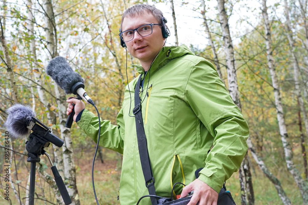 Fototapeta premium The guy with myerophne and headphones is recording the sounds of nature. Recording Ambient Sounds