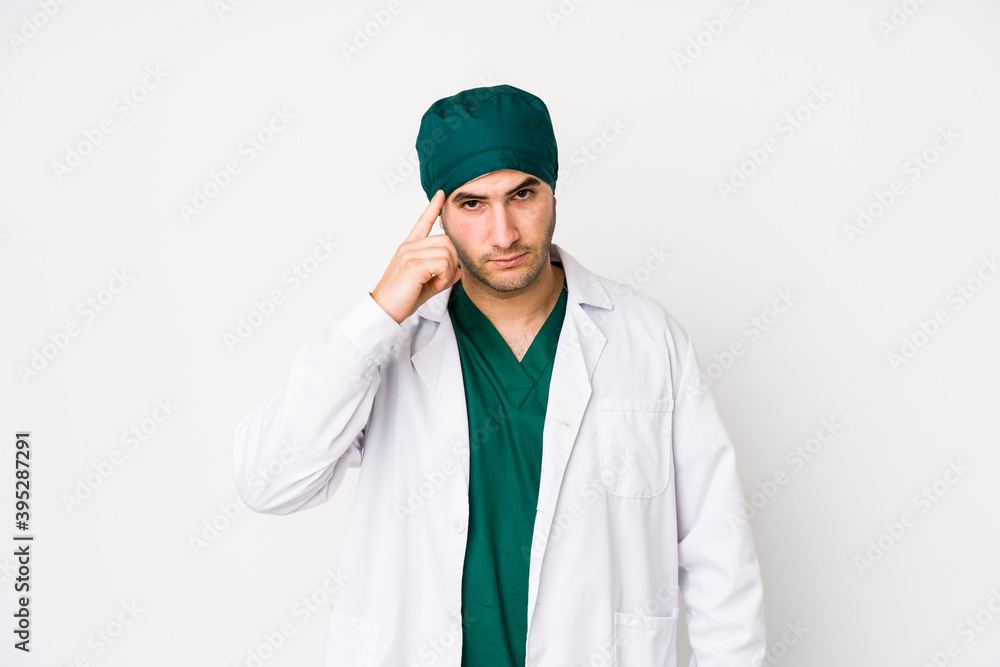 Young surgeon man isolated on white background pointing temple with finger, thinking, focused on a task. Young surgeon man isolated on white background pointing temple with finger, thinking, focused on a task.