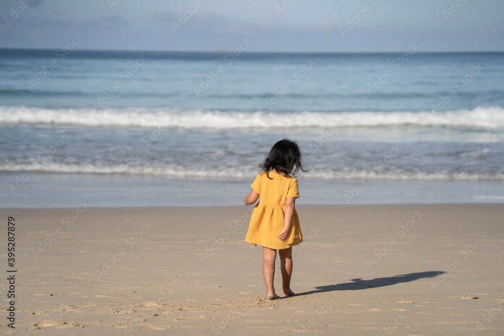 Cute little girl in yellow dress walking on the beach. Cute little girl in yellow dress walking on the beach.