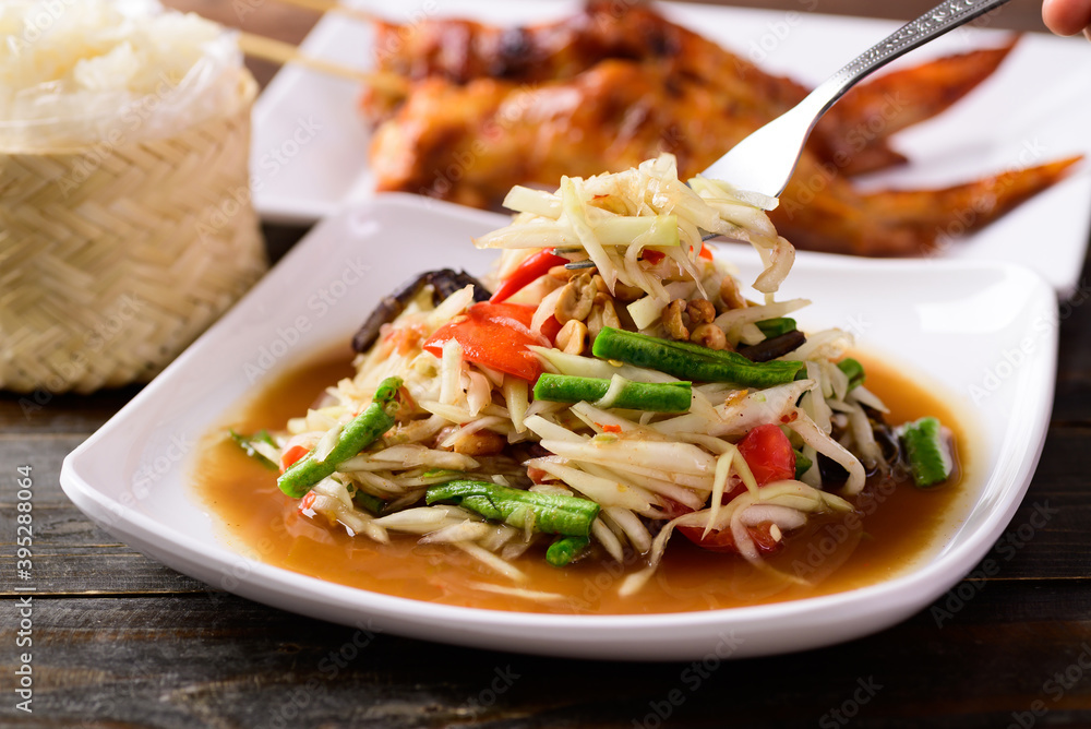 Thai food (Som Tum), Spicy green papaya salad eating with grilled chicken wing and sticky rice