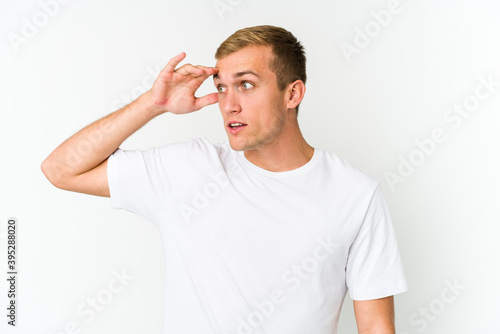 Young caucasian handsome man looking far away keeping hand on forehead. © Asier