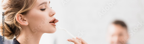 Businesswoman eating with plastic fork during break in office on blurred background, 