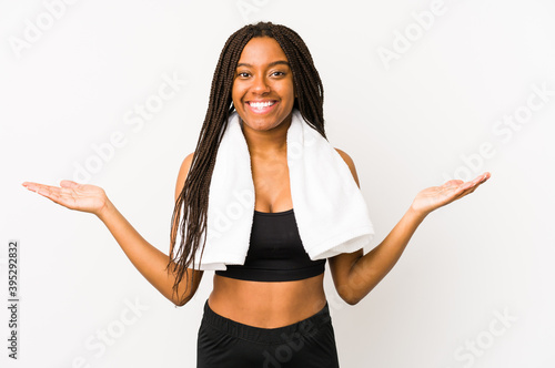 Young african american sport woman isolated makes scale with arms, feels happy and confident. © Asier