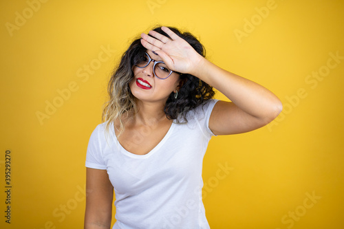 Young beautiful woman wearing casual white t-shirt over isolated yellow background Touching forehead for illness and fever, flu and cold, virus sick