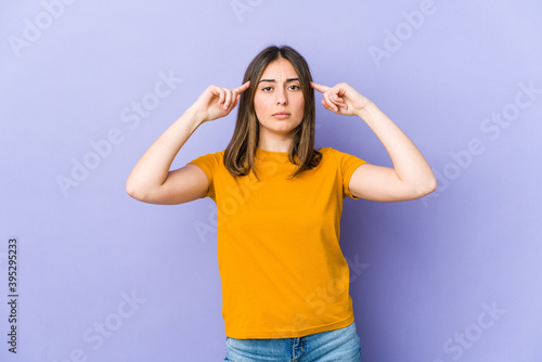 Young caucasian woman focused on a task, keeping forefingers pointing head.