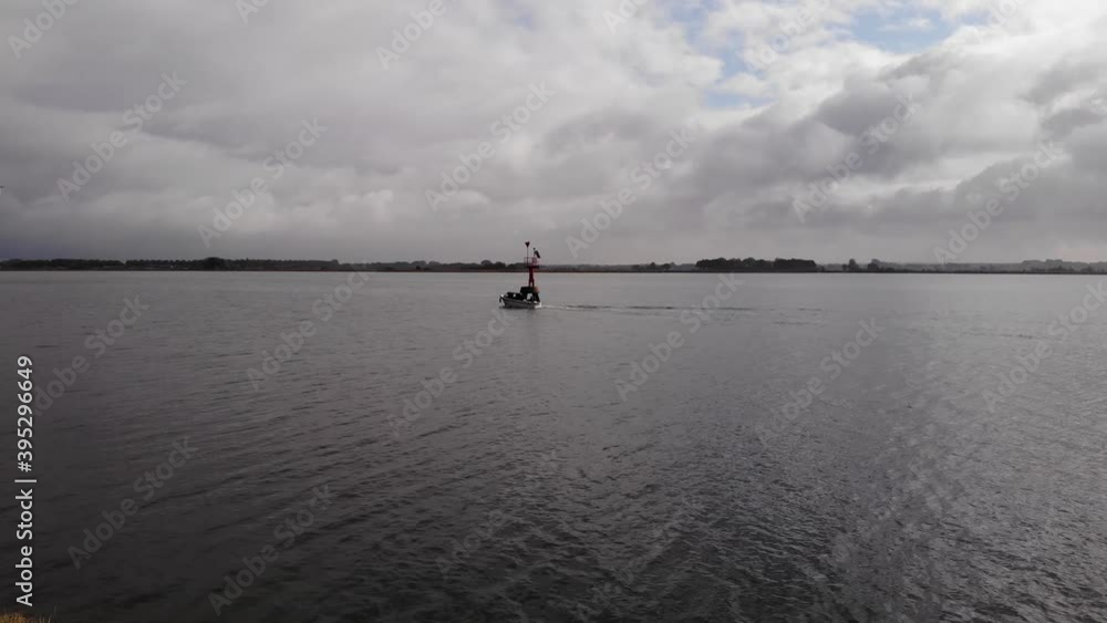 fishing boat and pleasure craft passing between the beacon of light on a fairway on a cloudy day in the netherlands. Drone steady shot fishing boat and pleasure craft passing between the beacon of light on a fairway on a cloudy day in the netherlands. Drone steady shot