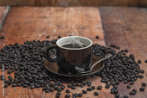 A cup of coffee with coffee beans over a wooden table.