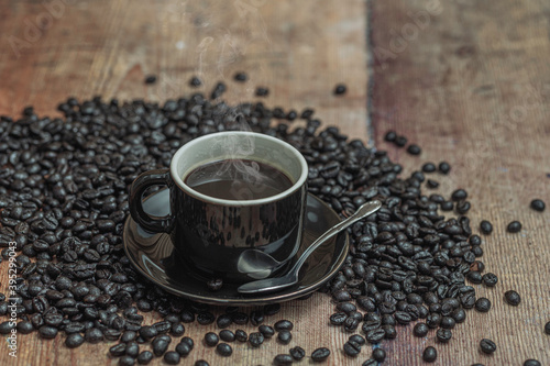 A cup of coffee with coffee beans over a wooden table.