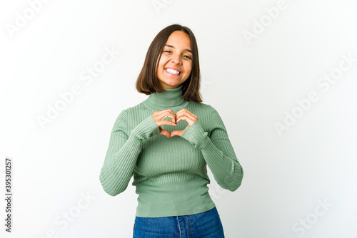 Young mixed race woman smiling and showing a heart shape with hands.