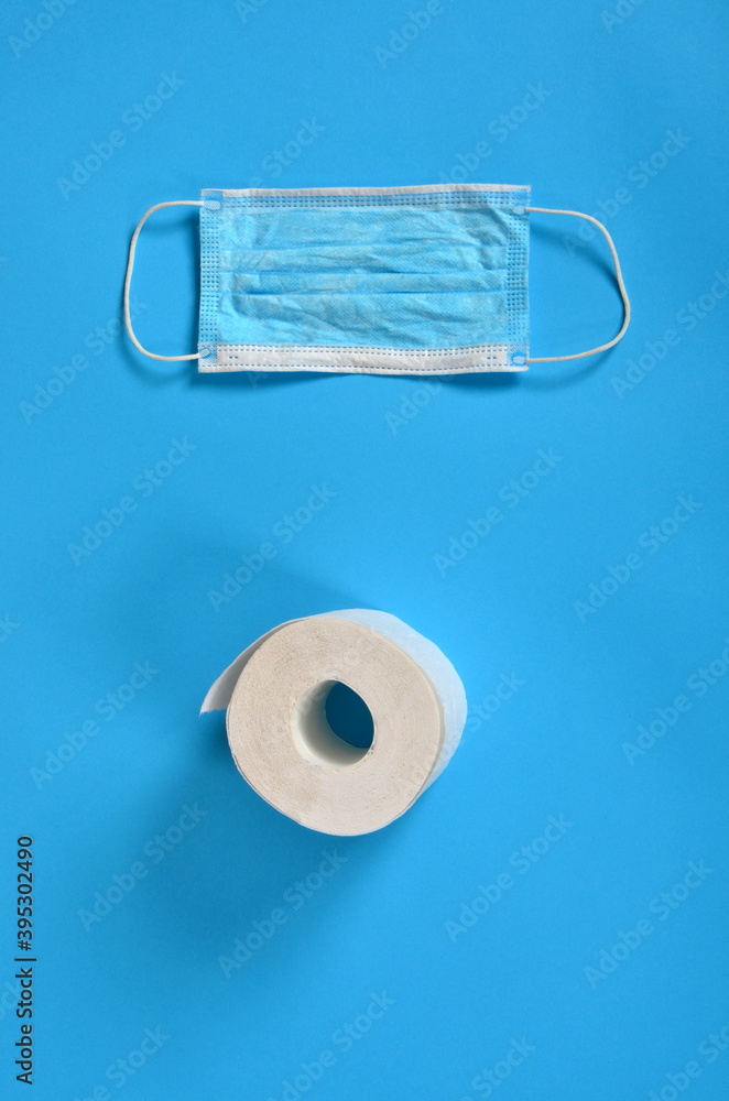 Obraz premium Blue Face protective masks and a roll of toilet paper on a blue background. Copy space, covid - 19
