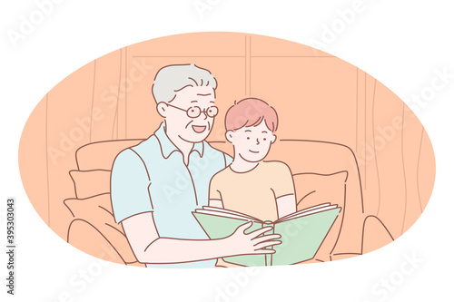 Happy family, parenthood, children concept. Happy grandfather sitting and reading book together with smiling grandson at home. Togetherness, happiness, grandparent, leisure, activity 