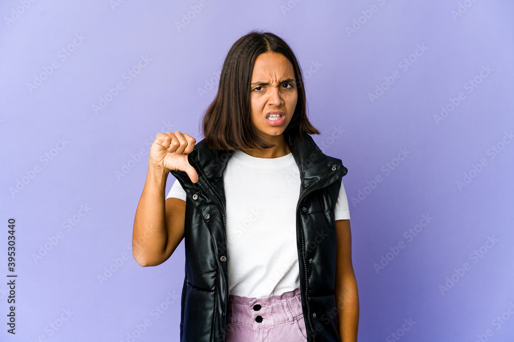 Young mixed race woman showing thumb down and expressing dislike. Young mixed race woman showing thumb down and expressing dislike.