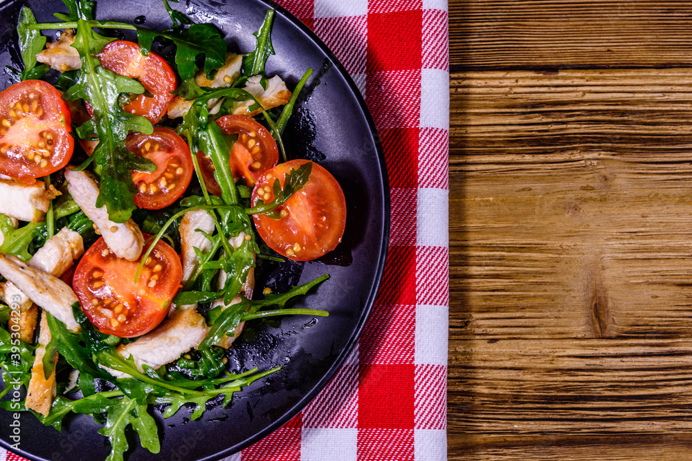 Roasted chicken breasts and salad with arugula and cherry tomatoes in a ceramic plate. Top view Roasted chicken breasts and salad with arugula and cherry tomatoes in a ceramic plate. Top view