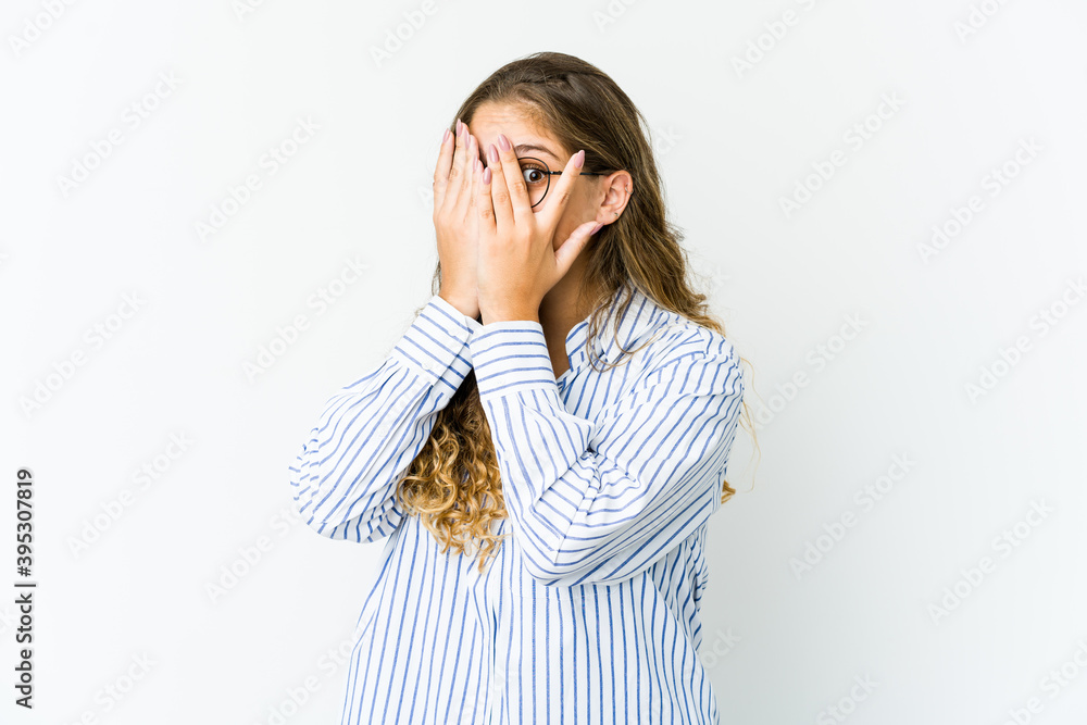 Young caucasian woman blink through fingers frightened and nervous.