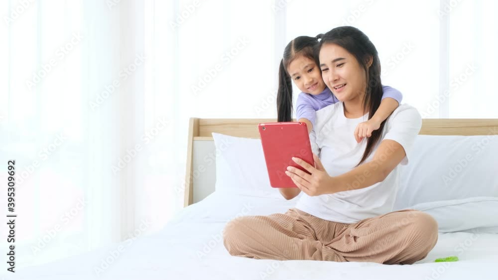 Asian little child girl and mother using tablet for video conference to family together on bed. Asian little child girl and mother using tablet for video conference to family together on bed.