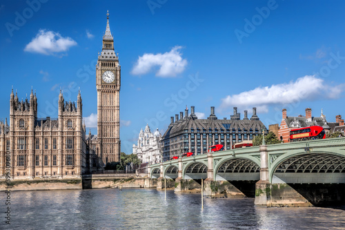 Big Ben and Houses of Parliament with red buses on the bridge in London, England, UK