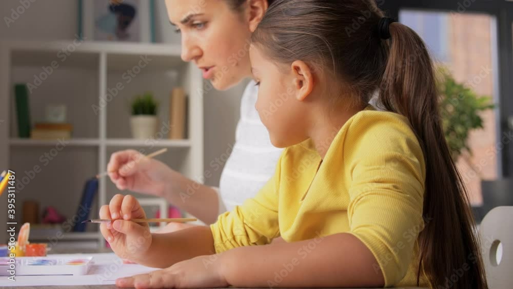 family, motherhood and leisure concept - mother spending time with her little daughter drawing with colors at home family, motherhood and leisure concept - mother spending time with her little daughter drawing with colors at home