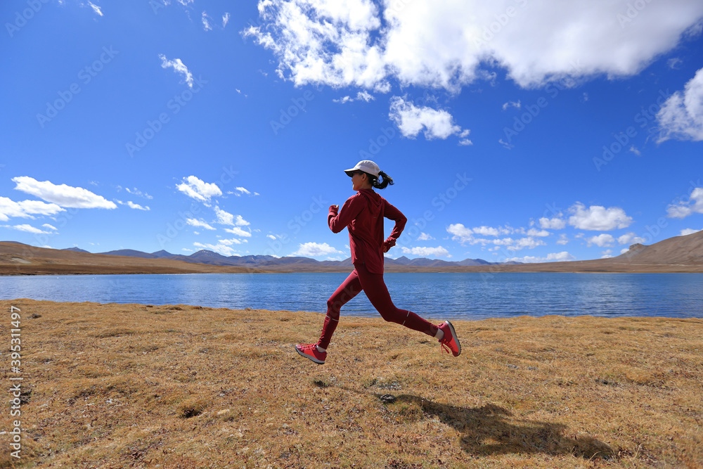 Woman trail runner cross country running in winter lakeside Woman trail runner cross country running in winter lakeside