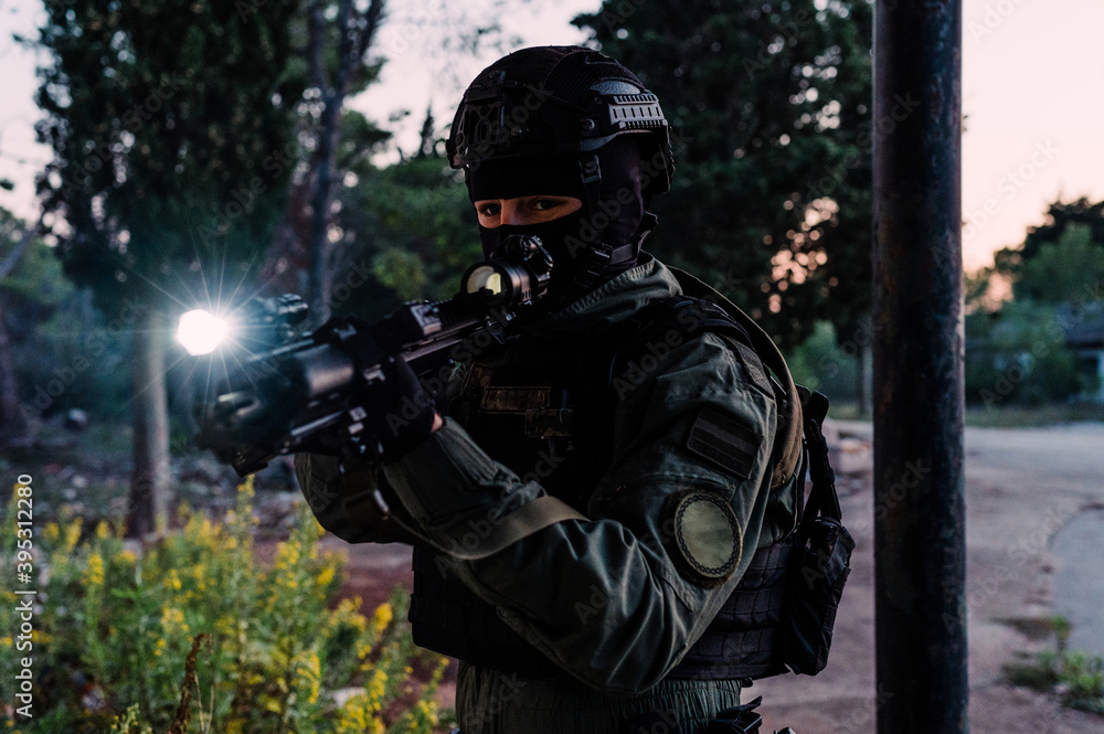 Man reenacting special unit of Croatian military police. Wearing green jumpsuit with black add-ons and assault rifle G36.