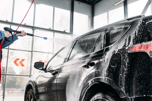 Woman washing his car in a self-service car wash station.Car wash self-service. 