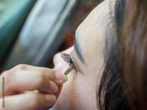 Canvastavla Closeup photo of a woman placing fake eyelashes to her eyelid with tweezers
