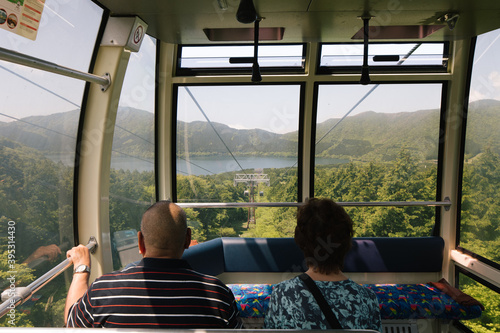 cable cart passengers look over beautiful view on nature green hills and lake old couple in japan