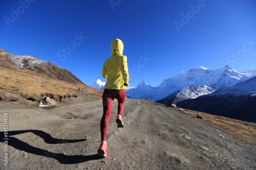 Woman trail runner cross country running in winter mountains