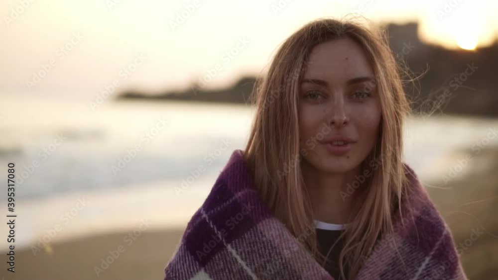 Portrait of a girl wrapped in a blanket on the beach in autumn Portrait of a girl wrapped in a blanket on the beach in autumn