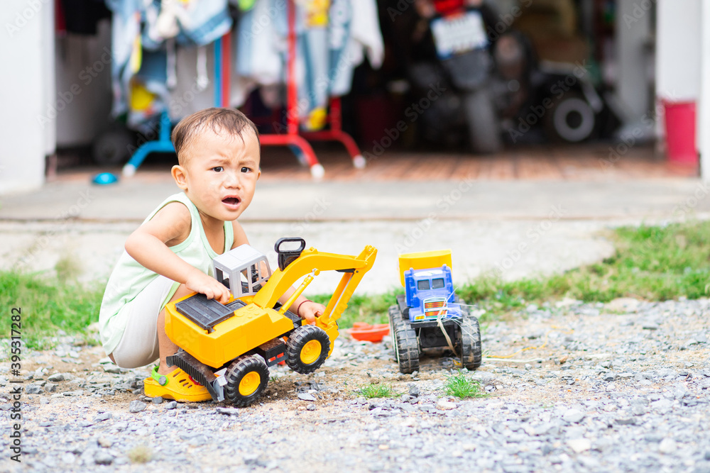 Little Asian kid playing on ground with his excavator toy Little Asian kid playing on ground with his excavator toy