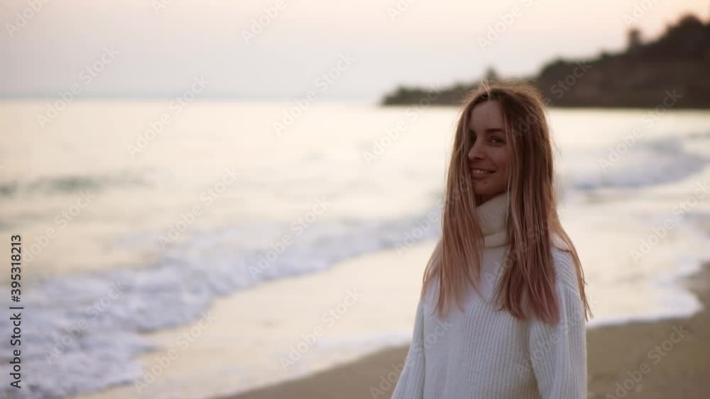 Portraitof a blonde woman looks to the camera, relaxfuly walks along the seashore Portraitof a blonde woman looks to the camera, relaxfuly walks along the seashore