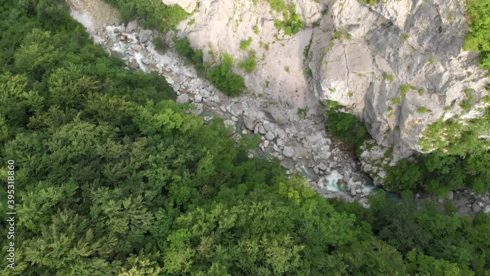 Drone lifts above secluded canyon with wild river and big rocks in summer Drone lifts above secluded canyon with wild river and big rocks in summer
